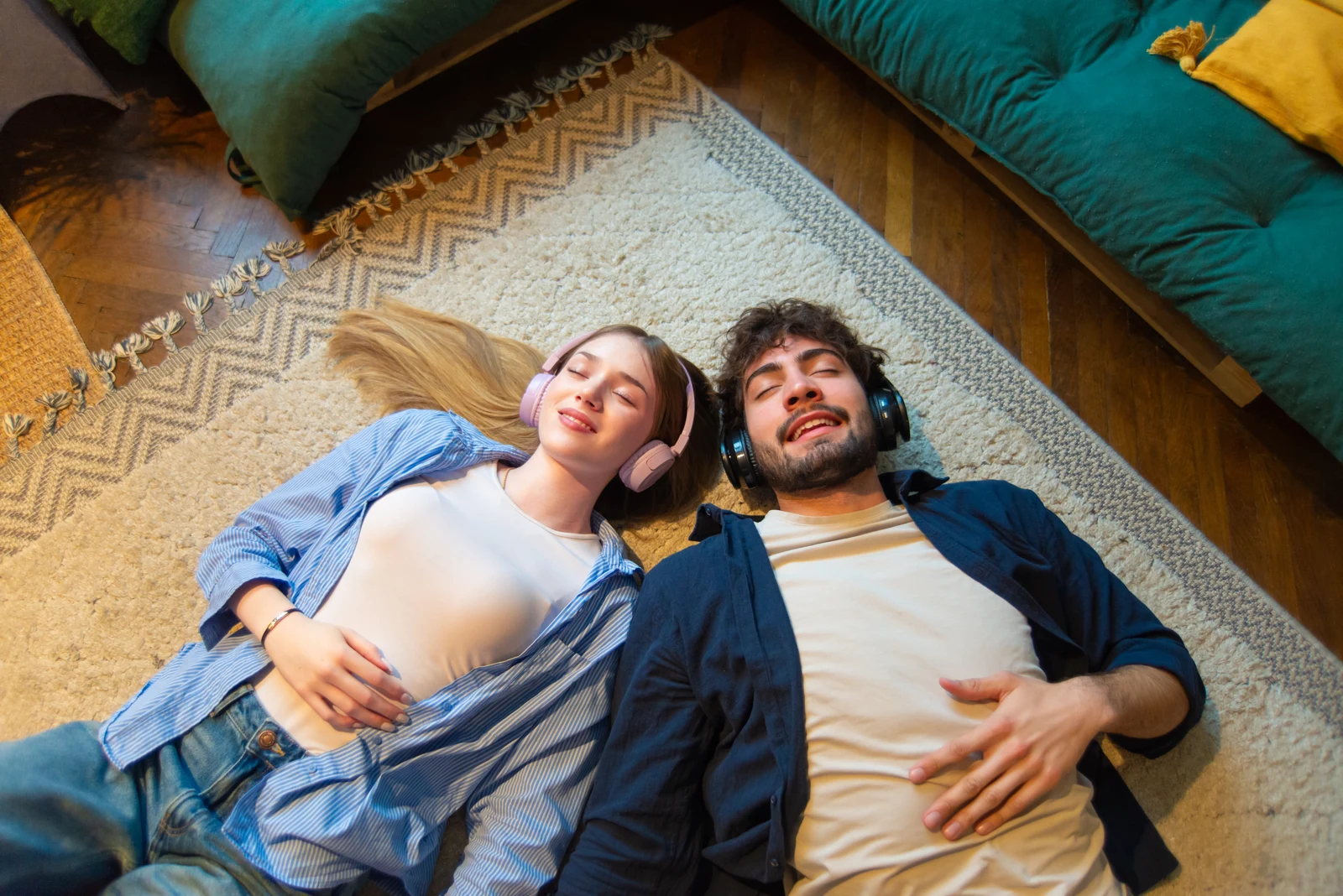 Two adults lying beside each other on the floor wearing headphones.