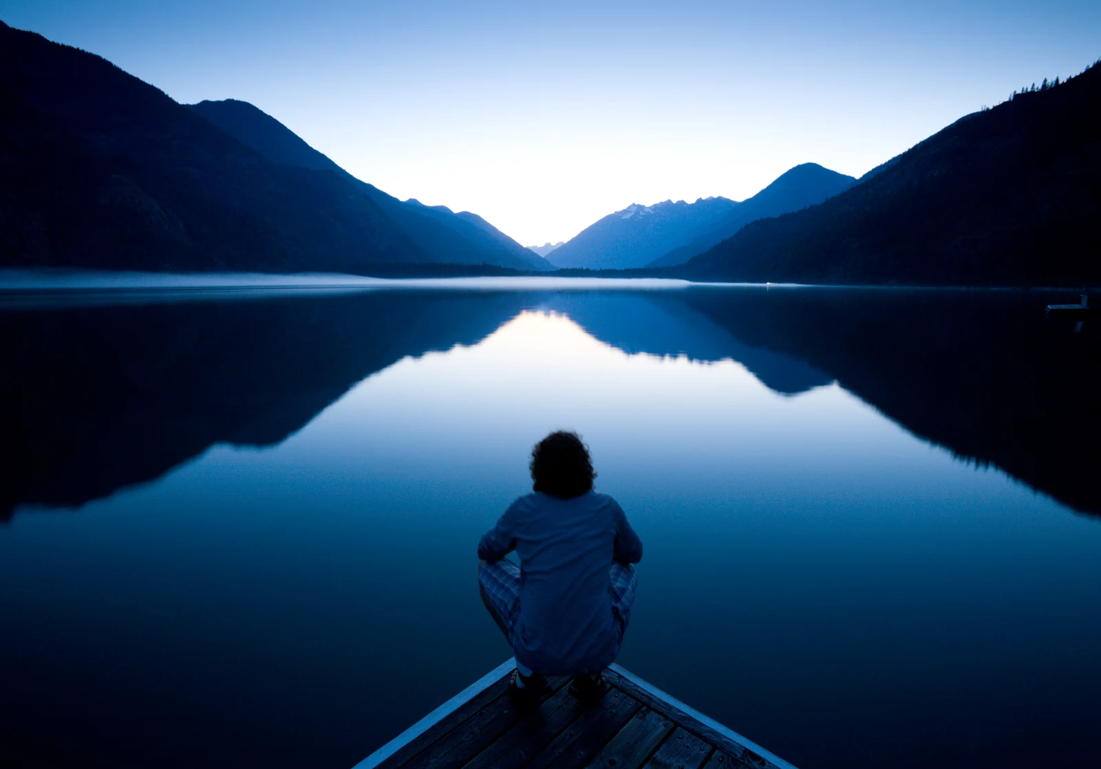 A person looking across a mountain lake.