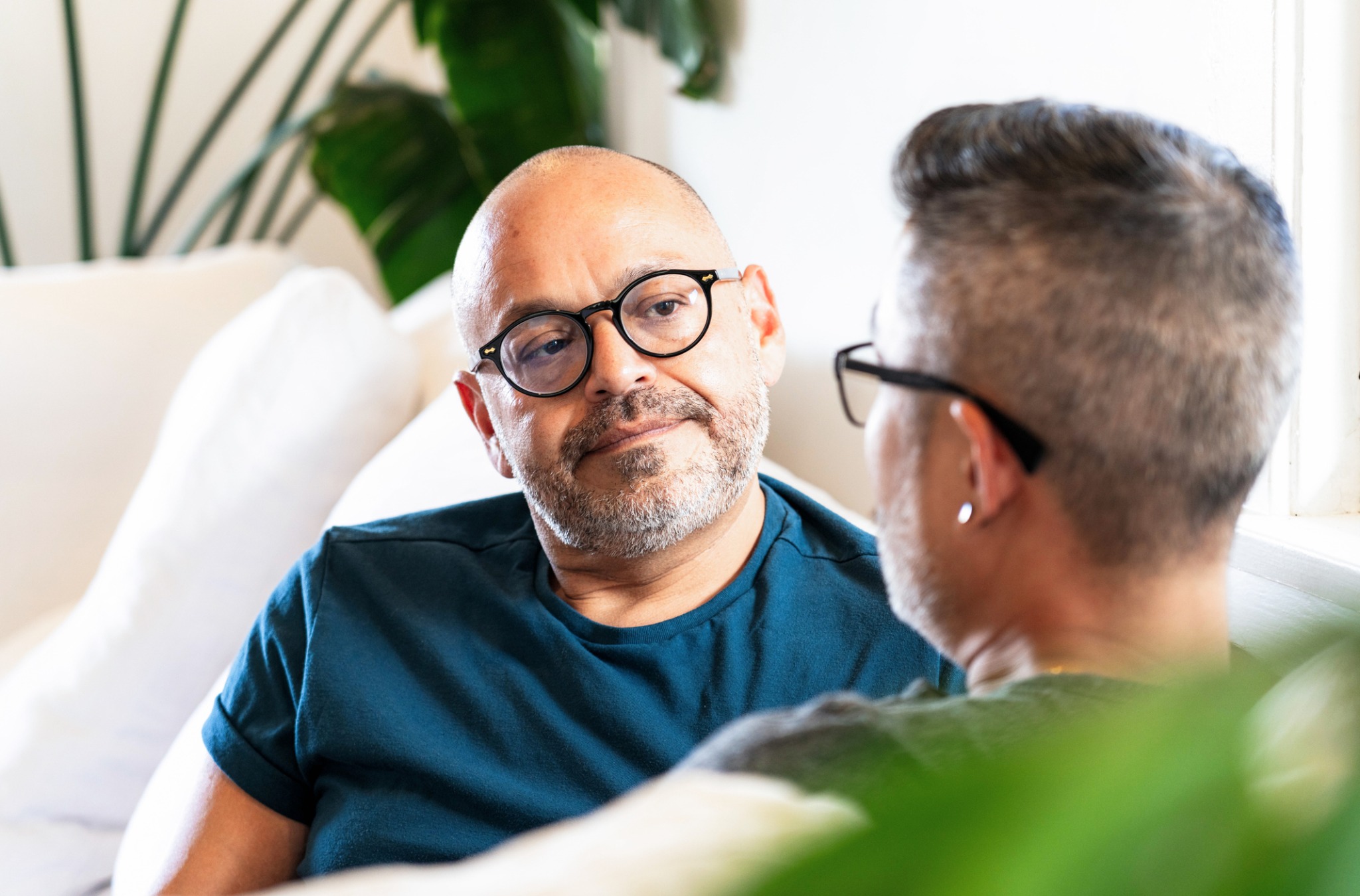 Two men seated face to face in conversation at home.